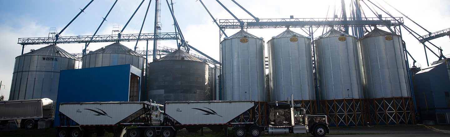 Vue latérale du Tem Ag Center avec un camion de transport de céréales arrêté le long de certains silos.